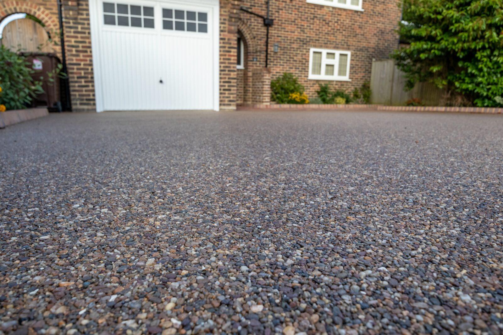 a,dark,coloured,resin,driveway,at,the,front,of,a